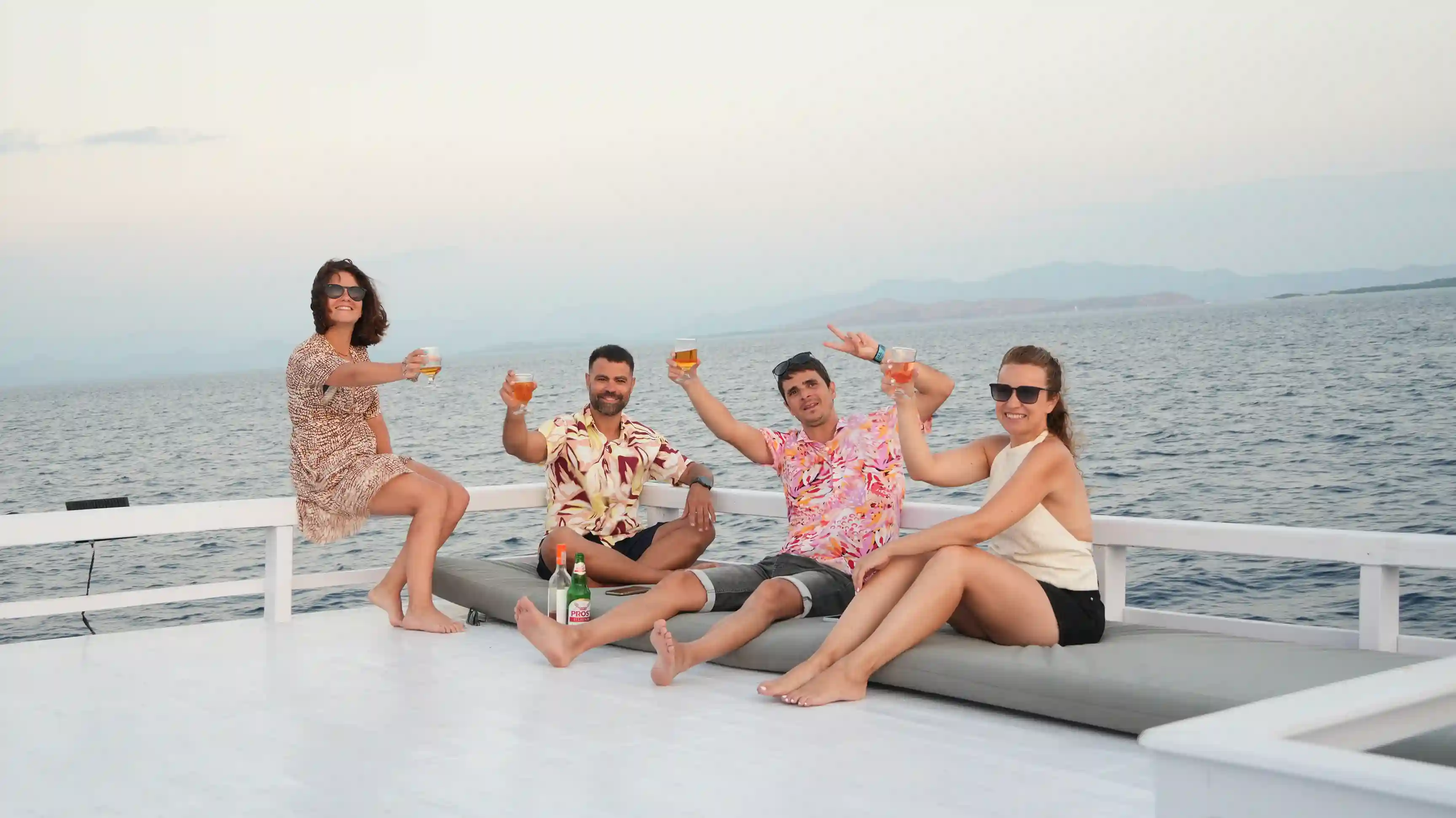 Guests toasting together on deck at sunset on the Komodo Liveaboard Open Trip