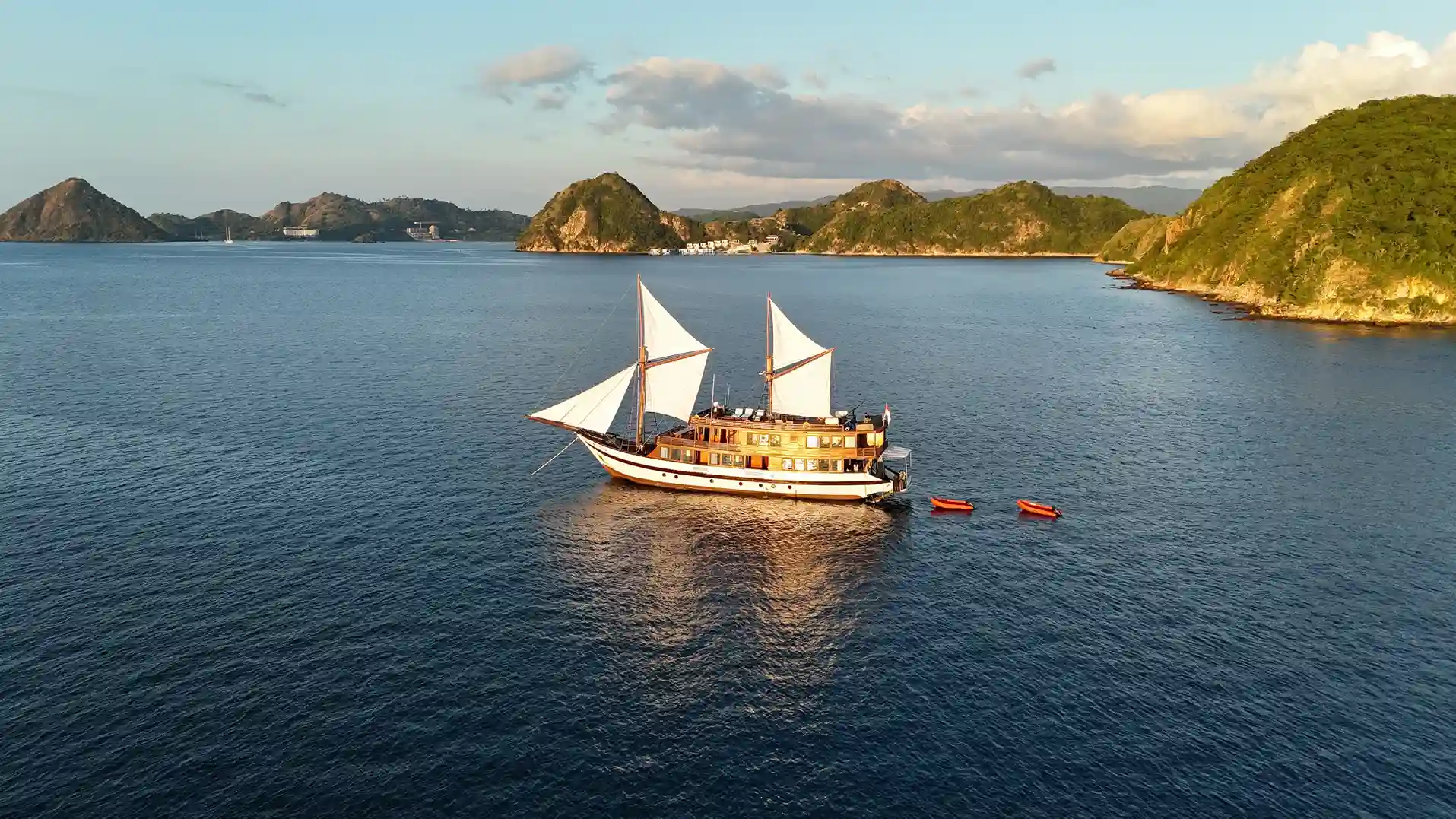 Phinisi charter sailing through the Komodo archipelago at sunset