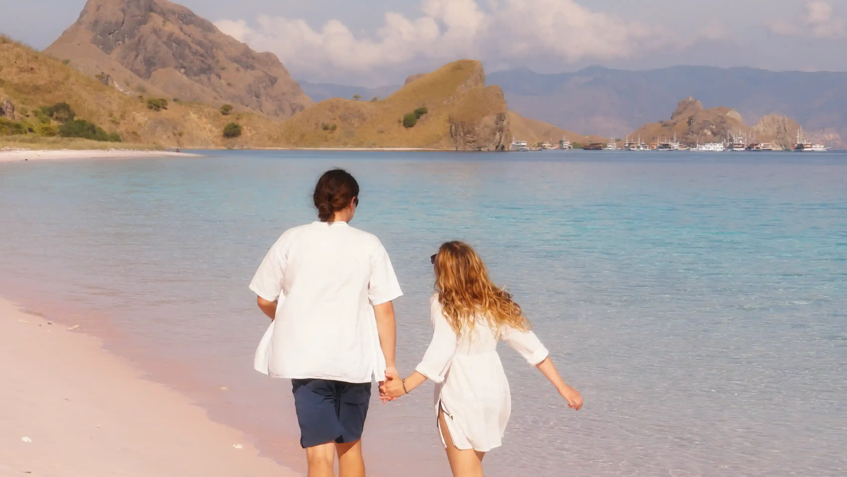 Couple relaxing on a sunset beach near their liveaboard