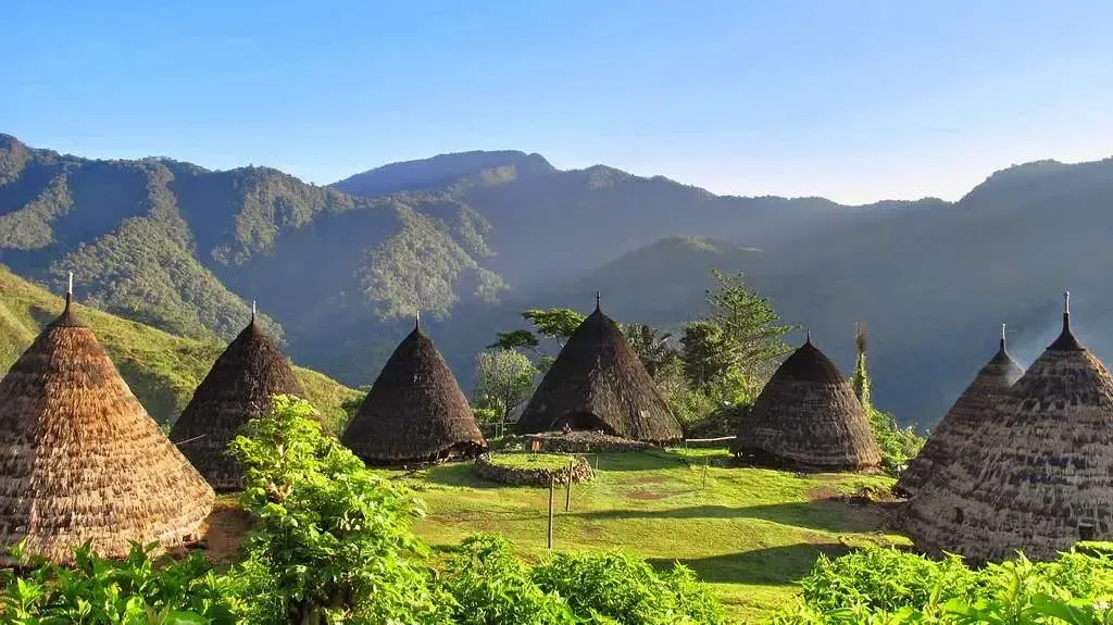 Travelers watching sunset over the Flores archipelago -- illustrative image; Wae Rebo Village itself lies inland in the highlands