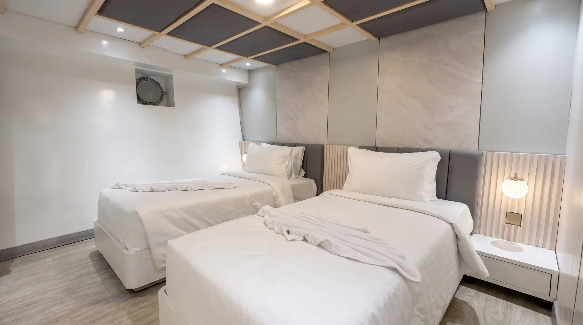 Grand Deluxe twin-bed cabin on Lasha Phinisi Cruise with porthole view
