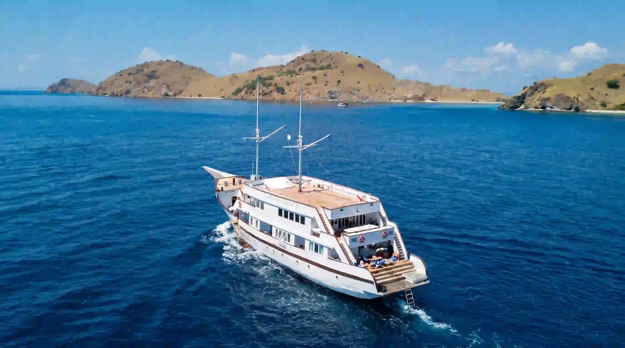 Lasha Phinisi Cruise underway across deep blue water in Komodo National Park